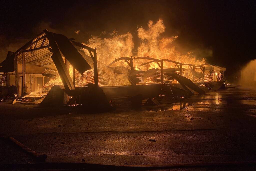 Brandweer bestrijdt grote uitslaande brand in twee loodsen