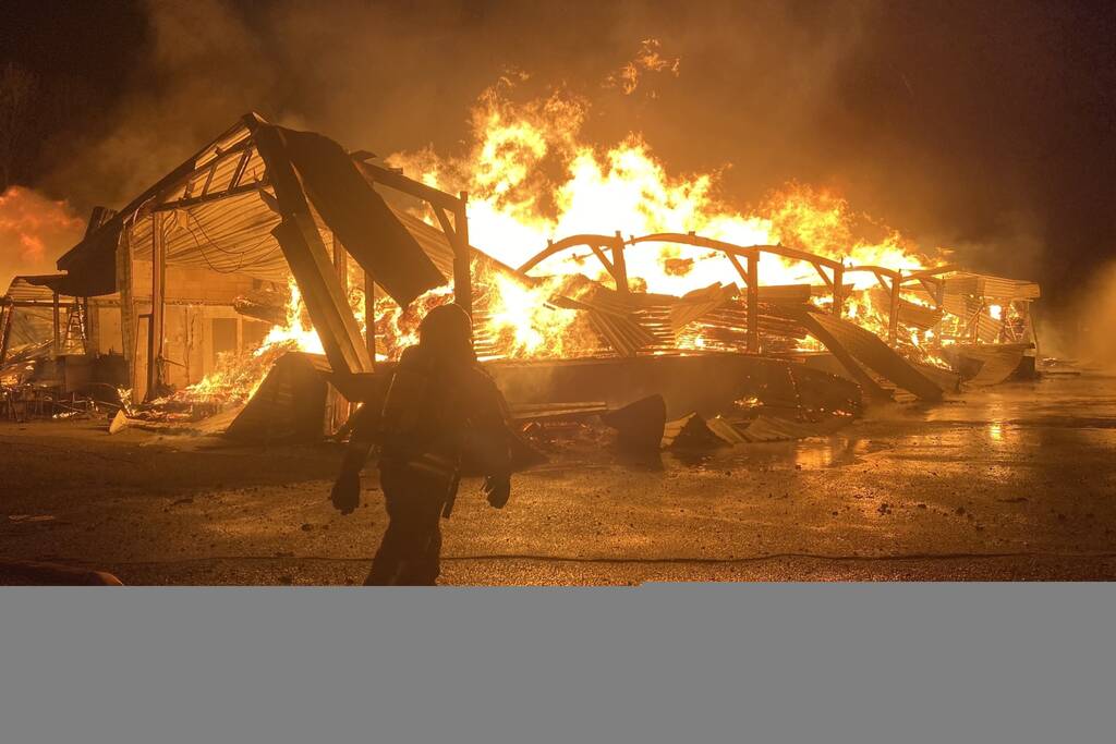 Brandweer bestrijdt grote uitslaande brand in twee loodsen