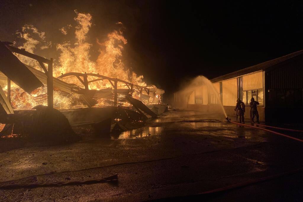 Brandweer bestrijdt grote uitslaande brand in twee loodsen