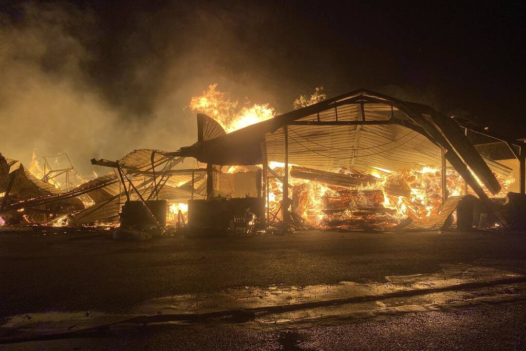 Brandweer bestrijdt grote uitslaande brand in twee loodsen