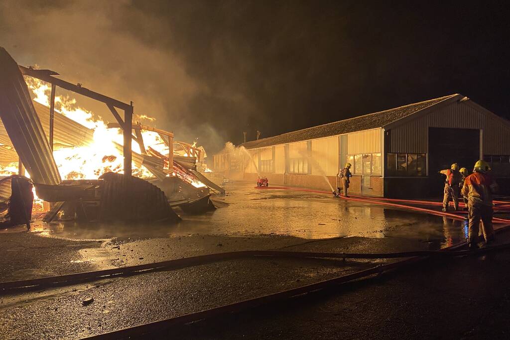 Brandweer bestrijdt grote uitslaande brand in twee loodsen