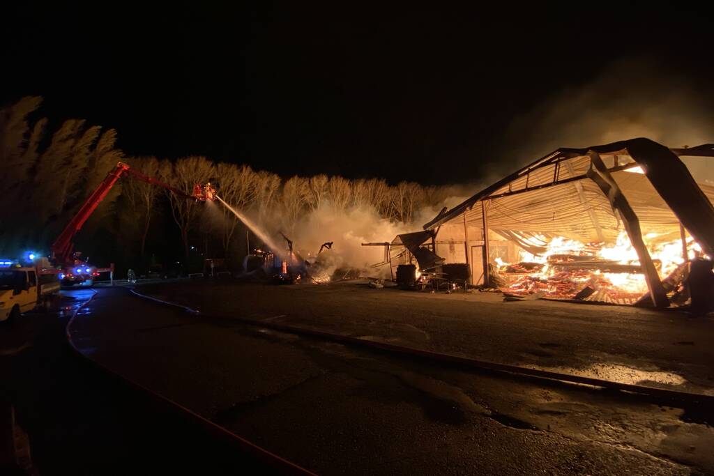 Brandweer bestrijdt grote uitslaande brand in twee loodsen