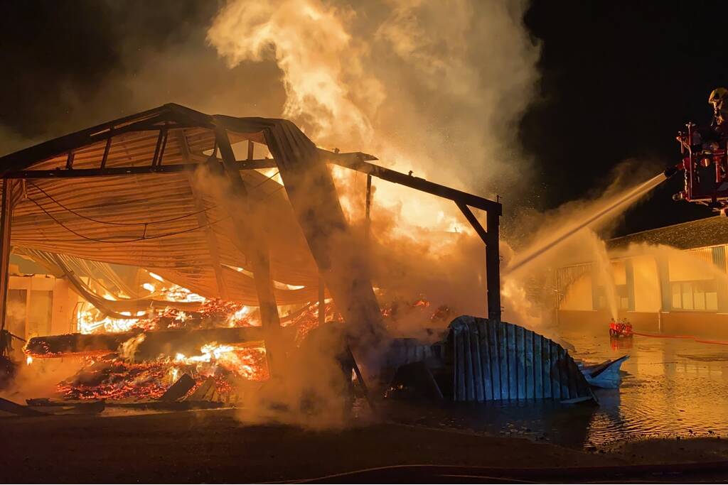 Brandweer bestrijdt grote uitslaande brand in twee loodsen