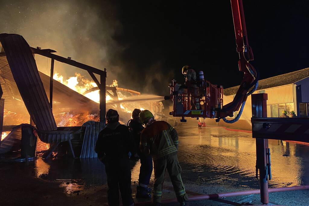 Brandweer bestrijdt grote uitslaande brand in twee loodsen