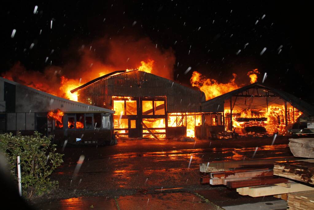 Brandweer bestrijdt grote uitslaande brand in twee loodsen