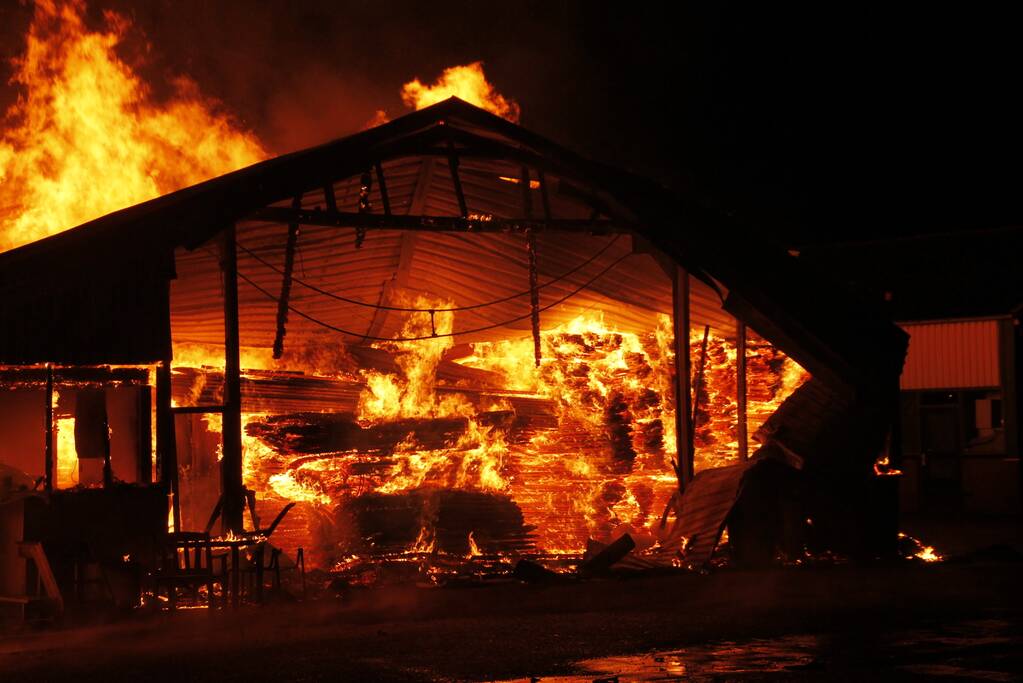 Brandweer bestrijdt grote uitslaande brand in twee loodsen