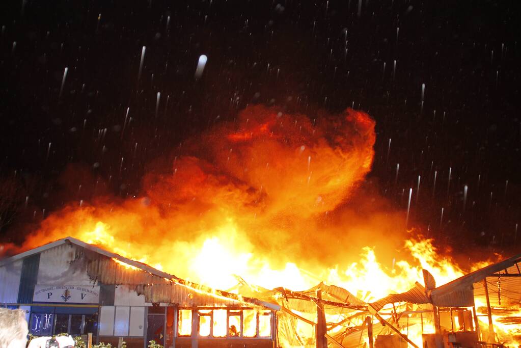 Brandweer bestrijdt grote uitslaande brand in twee loodsen