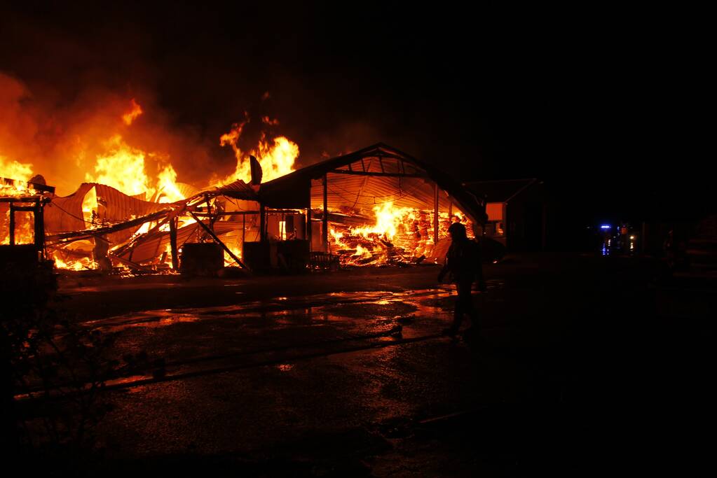 Brandweer bestrijdt grote uitslaande brand in twee loodsen