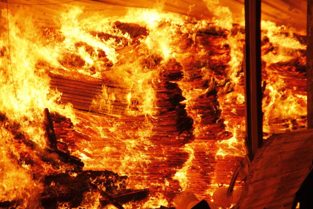 Brandweer bestrijdt grote uitslaande brand in twee loodsen