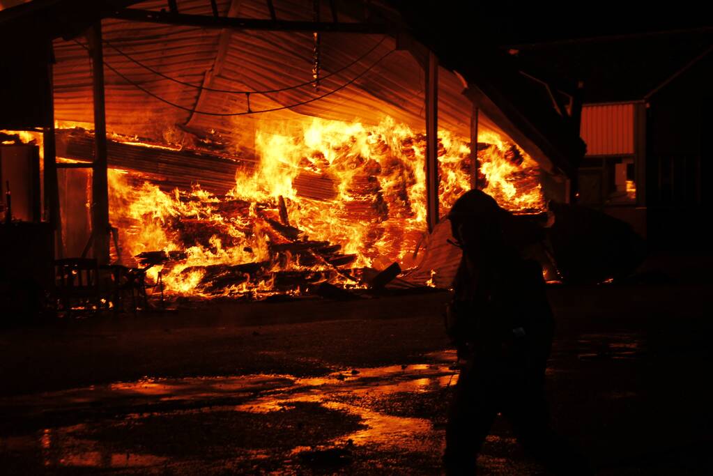 Brandweer bestrijdt grote uitslaande brand in twee loodsen