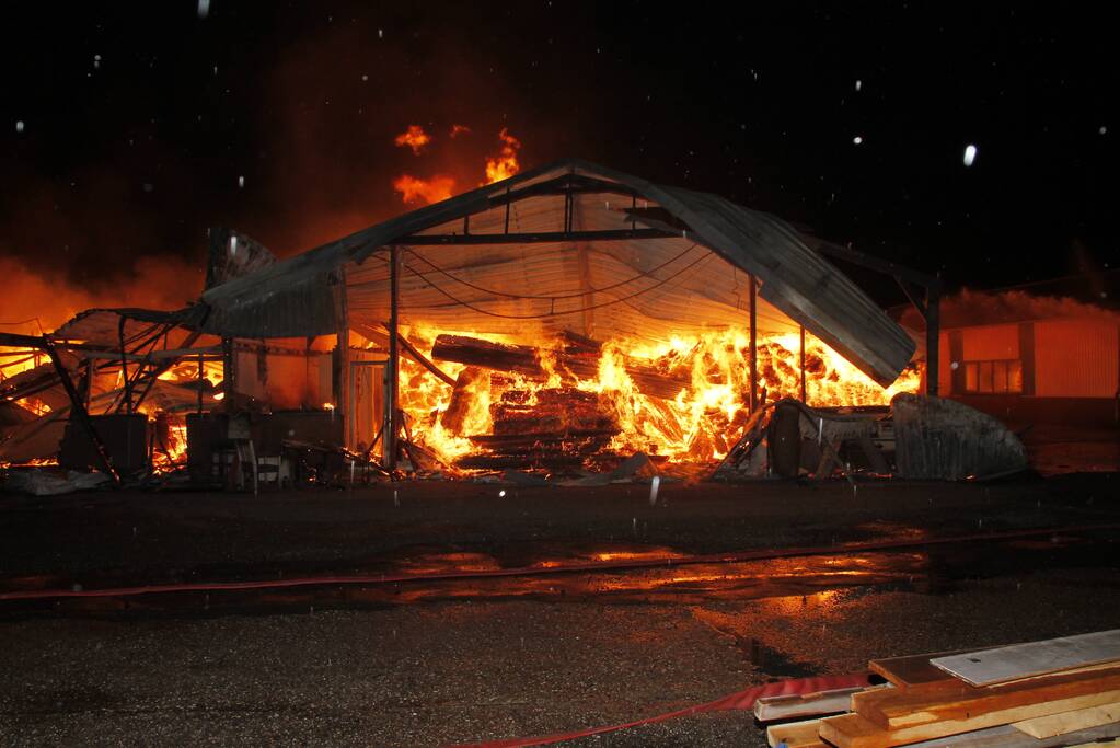 Brandweer bestrijdt grote uitslaande brand in twee loodsen