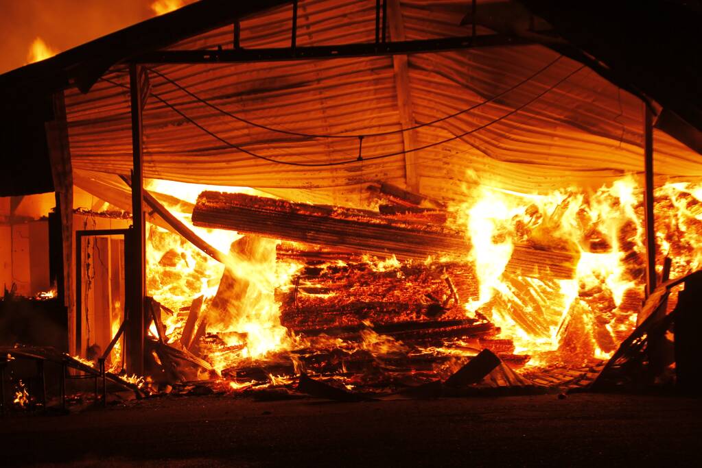 Brandweer bestrijdt grote uitslaande brand in twee loodsen