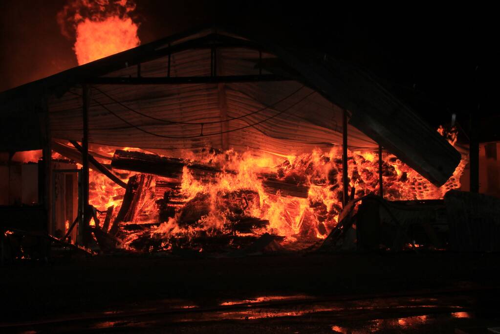 Brandweer bestrijdt grote uitslaande brand in twee loodsen