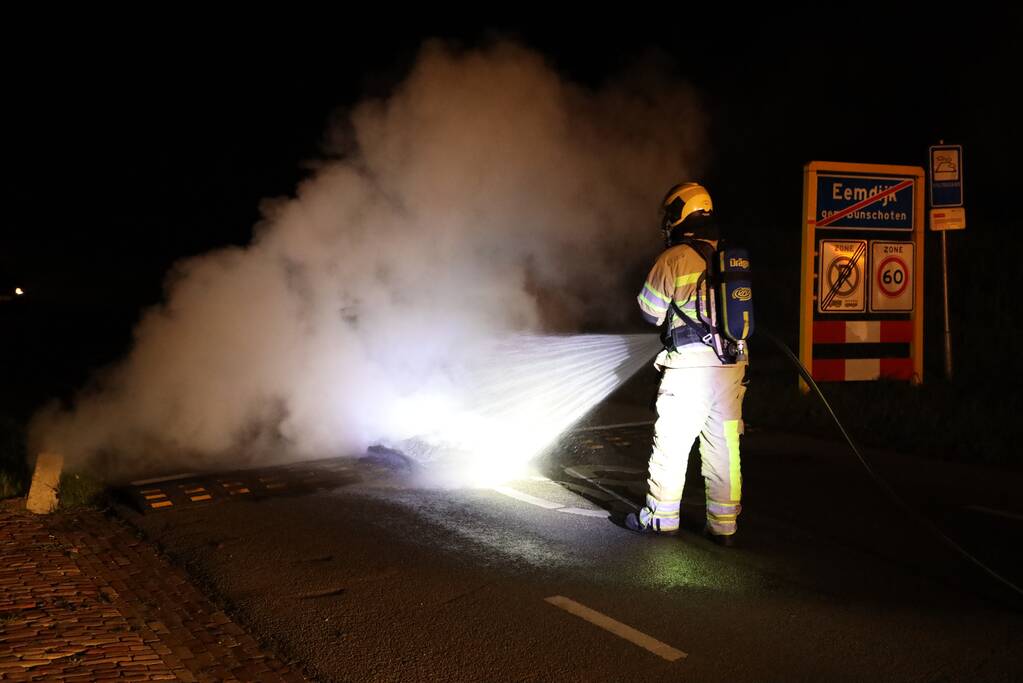 Brandweer blust brandende band op midden van weg