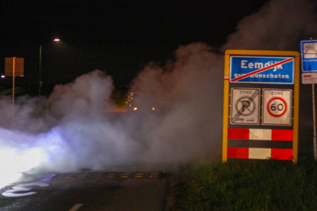 Brandweer blust brandende band op midden van weg