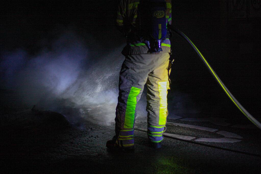Brandweer blust brandende band op midden van weg