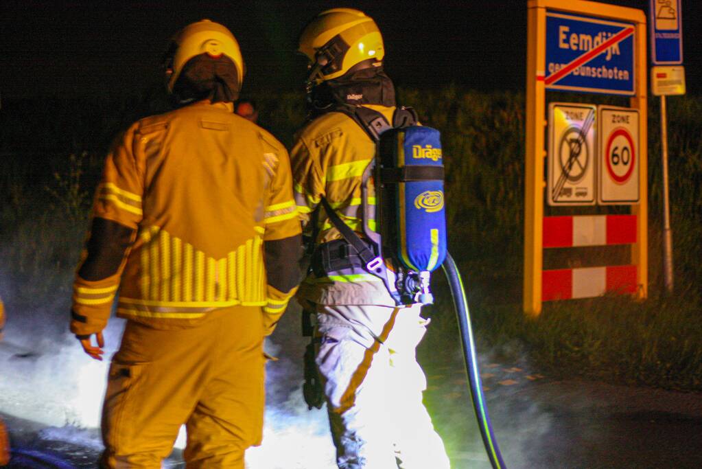 Brandweer blust brandende band op midden van weg