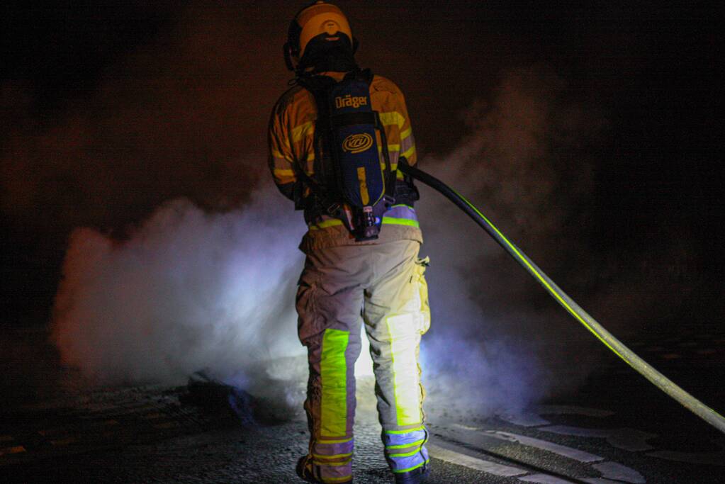 Brandweer blust brandende band op midden van weg