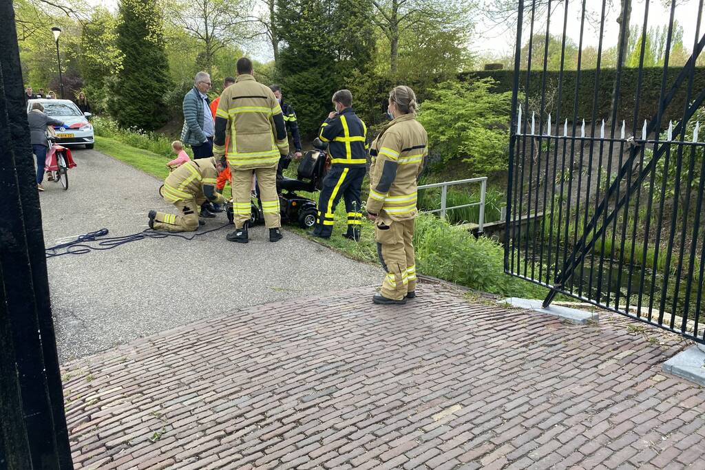 Persoon rijdt met scootmobiel het water in