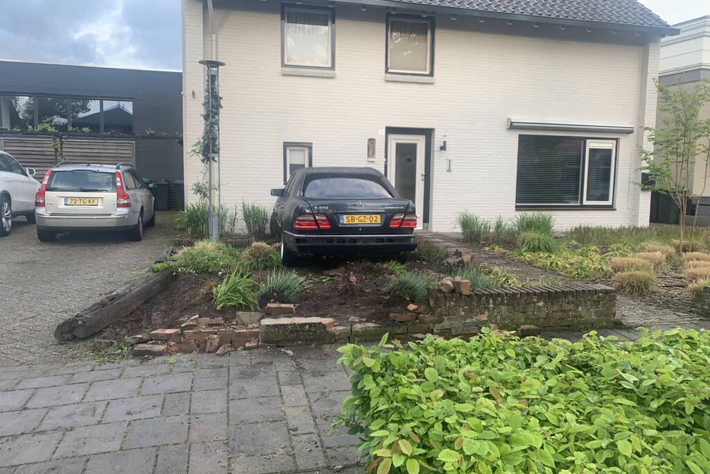 Auto rijdt door voortuin en tegen woning