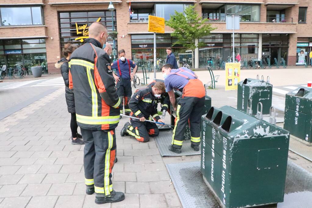 Brandweerman kruipt in ondergrondse papiercontainer voor verloren horloge