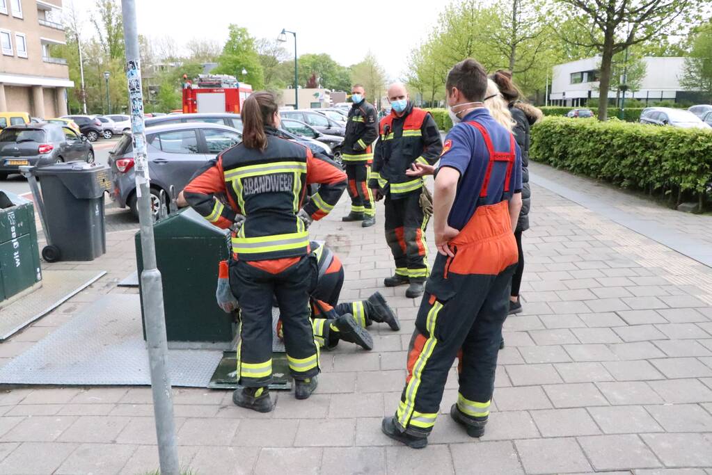 Brandweerman kruipt in ondergrondse papiercontainer voor verloren horloge