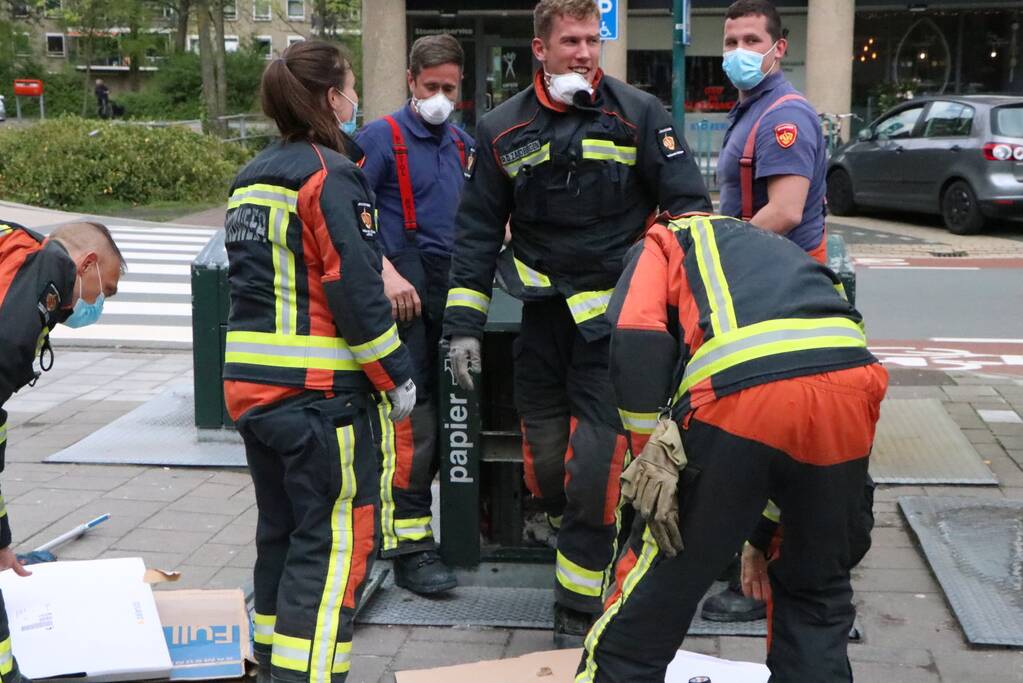 Brandweerman kruipt in ondergrondse papiercontainer voor verloren horloge