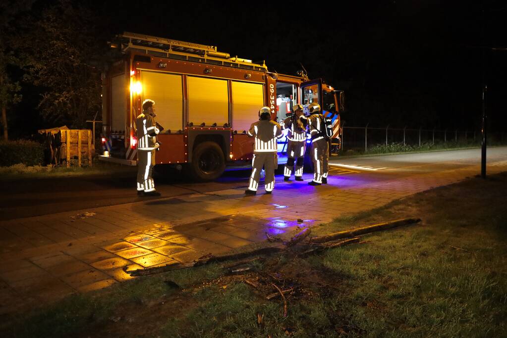 Brandweer blust brandende stukken hout