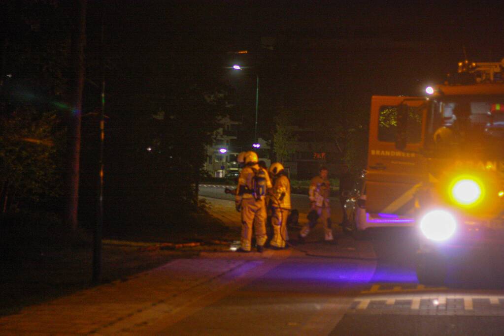 Brandweer blust brandende stukken hout
