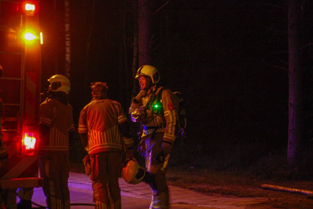Brandweer blust brandende stukken hout