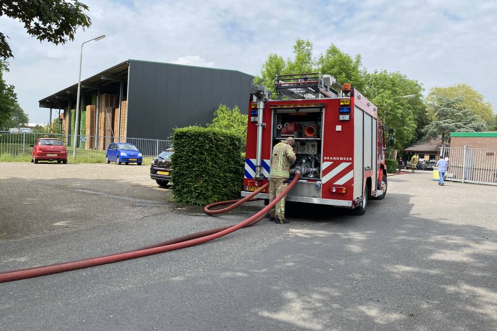 Brandweer blust brandende container met houtpulp bij houtbedrijf Rowood