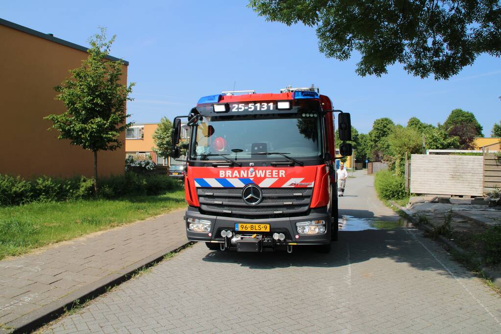 Brandweer blust in brand staande schutting