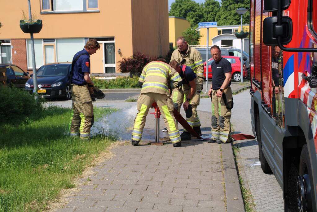 Brandweer blust in brand staande schutting