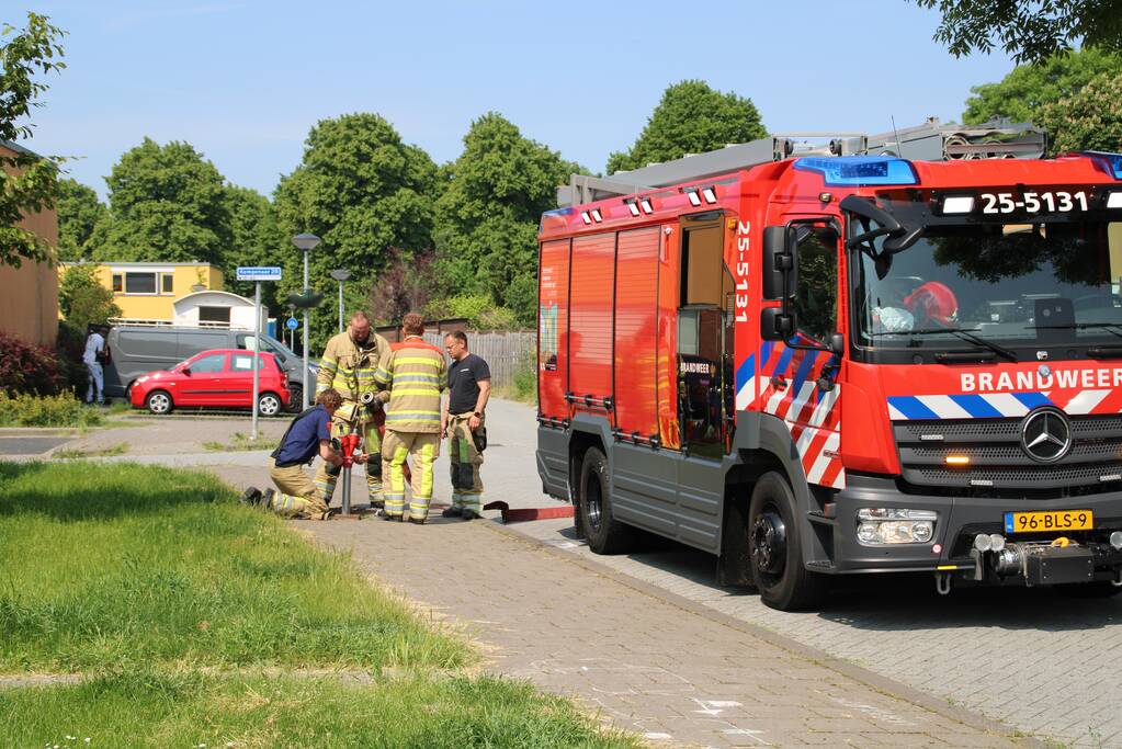 Brandweer blust in brand staande schutting