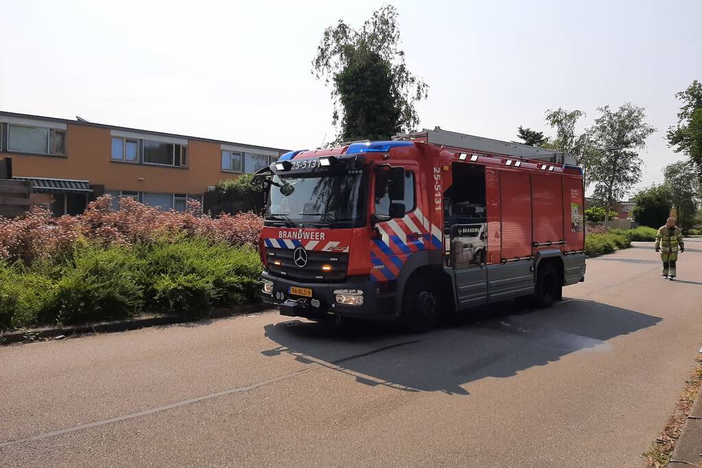 Brandweer blust in brand staande schutting