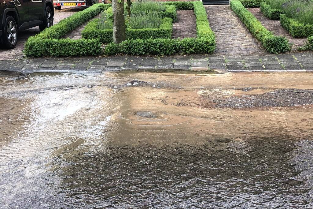 Straat onder water door gesprongen waterleiding