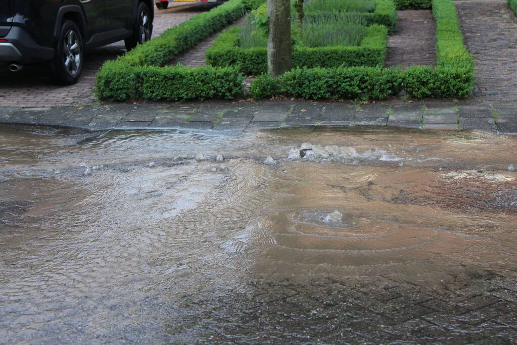 Straat onder water door gesprongen waterleiding