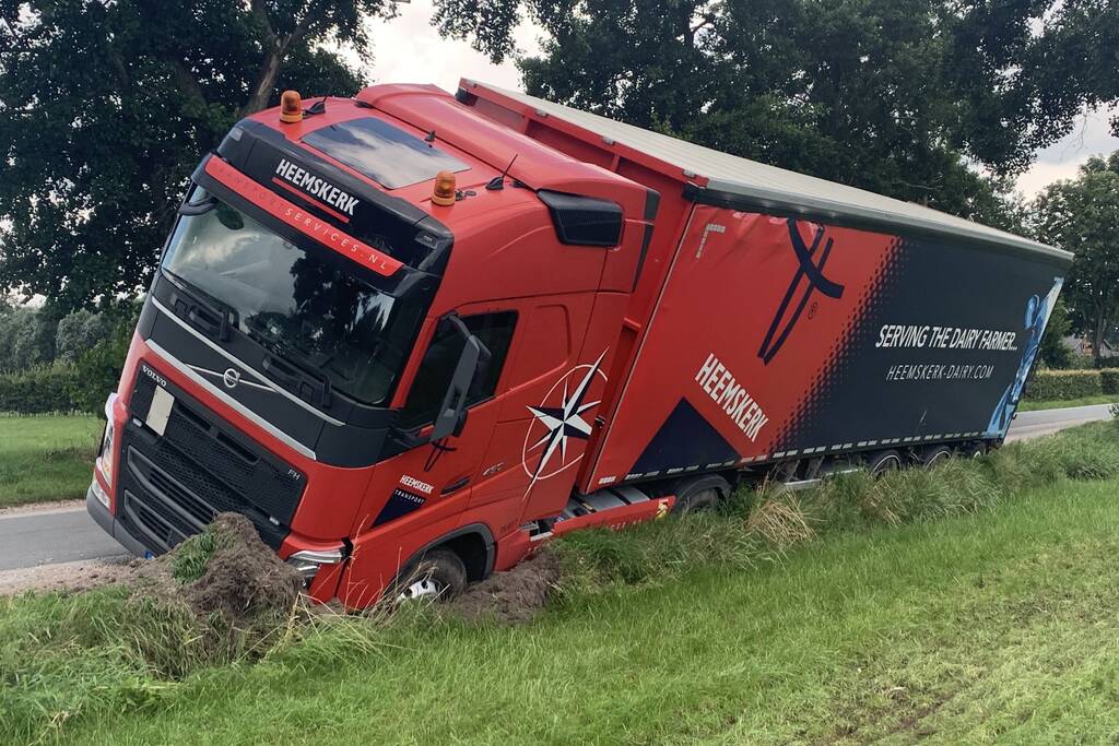 Vrachtwagen met oplegger komt vast te zitten in greppel