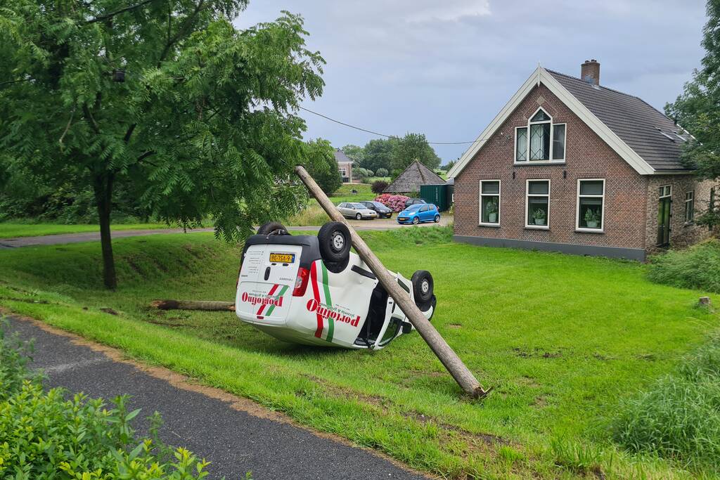 Bezorgauto slaat over de kop en ramt stroommast