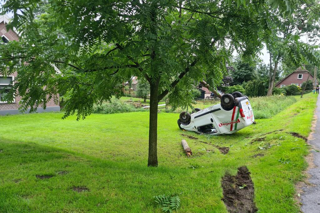 Bezorgauto slaat over de kop en ramt stroommast