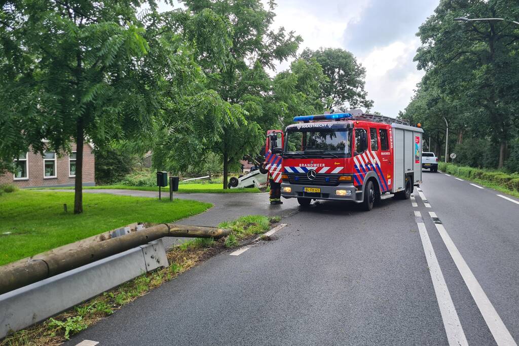 Bezorgauto slaat over de kop en ramt stroommast
