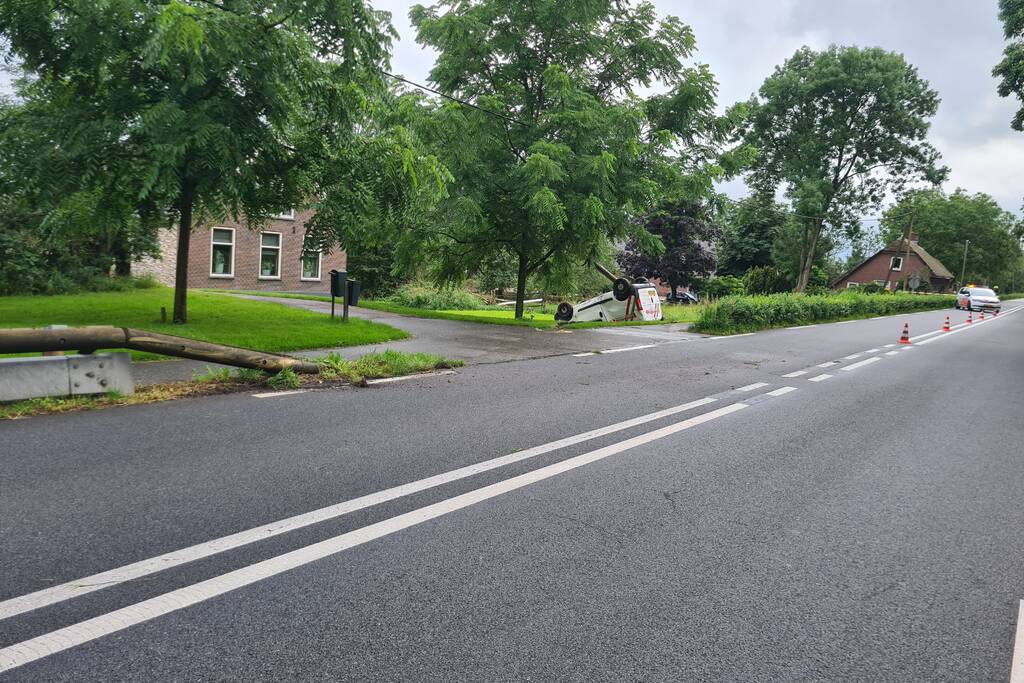 Bezorgauto slaat over de kop en ramt stroommast