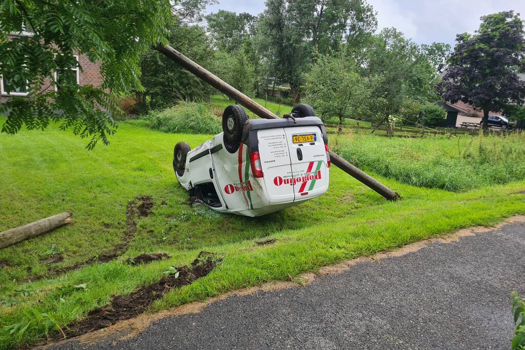 Bezorgauto slaat over de kop en ramt stroommast