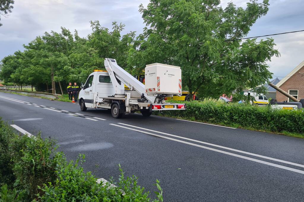Bezorgauto slaat over de kop en ramt stroommast