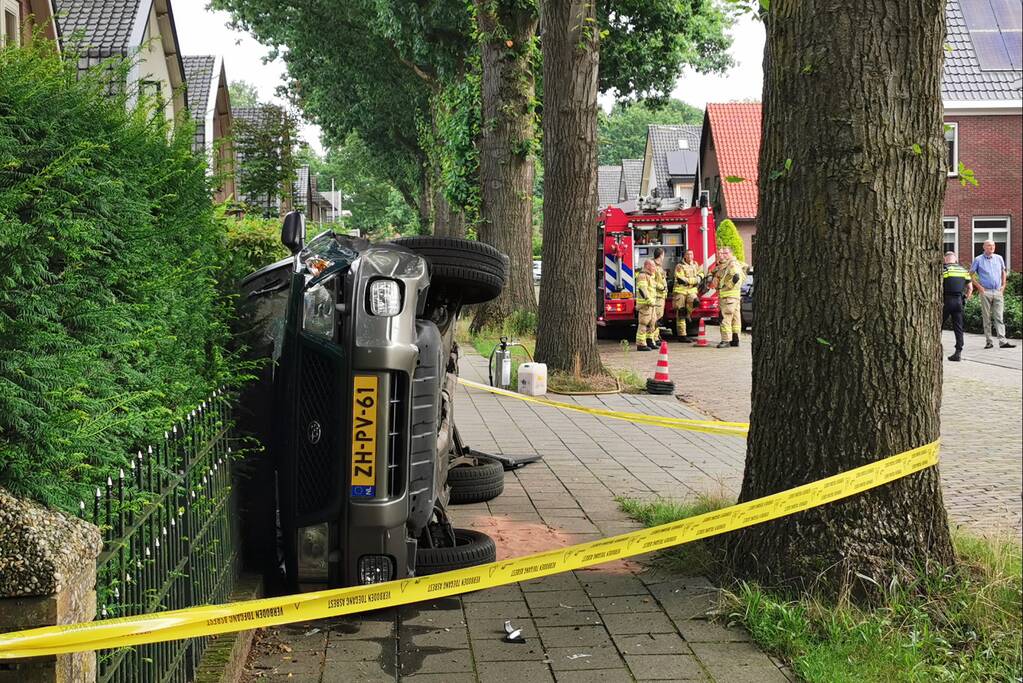 Auto belandt op zijn kant tegen hekwerk