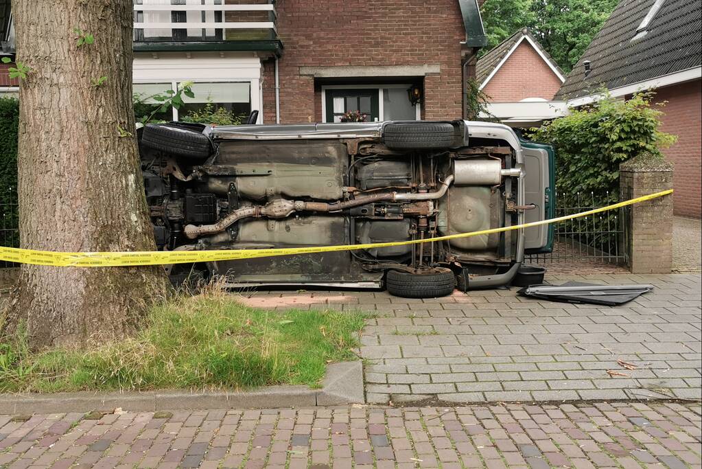 Auto belandt op zijn kant tegen hekwerk