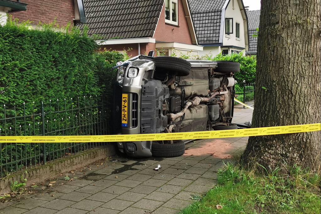 Auto belandt op zijn kant tegen hekwerk
