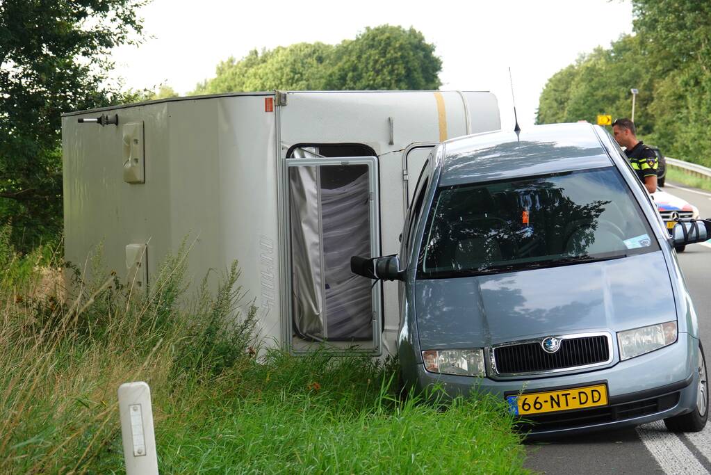 Auto met caravan belandt op zijn kant