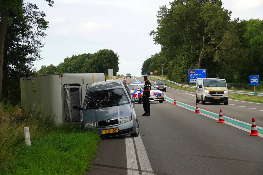Auto met caravan belandt op zijn kant