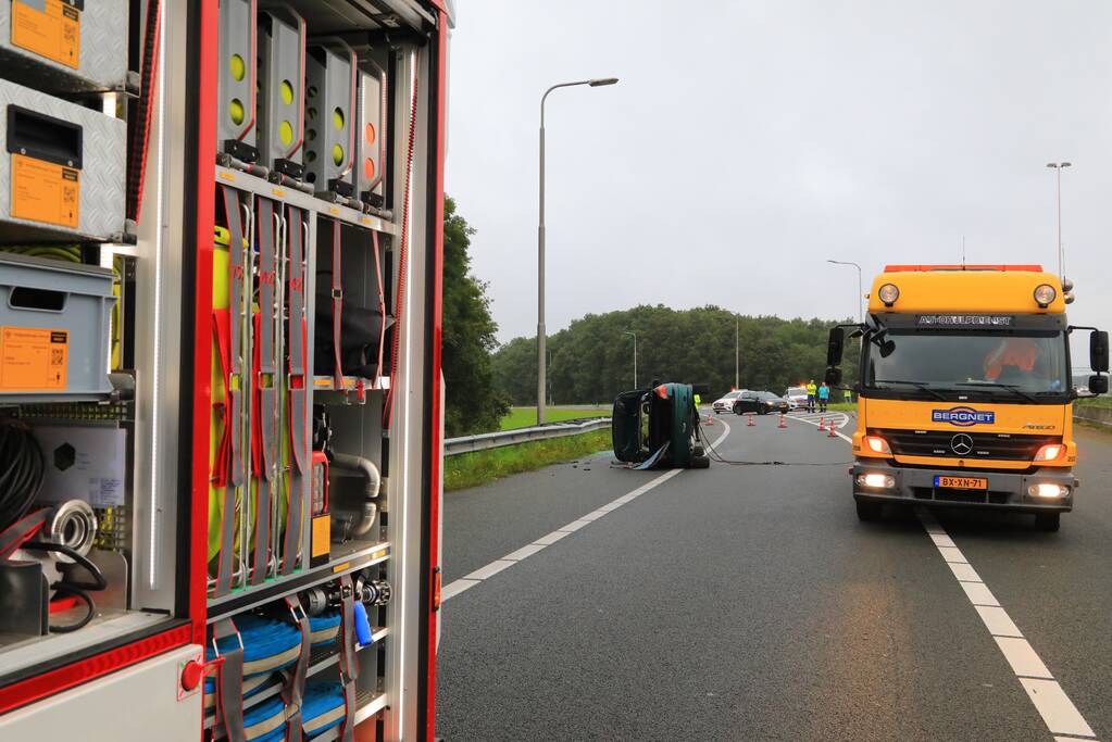 Auto glijdt over vangrail heen en belandt op zijn kop